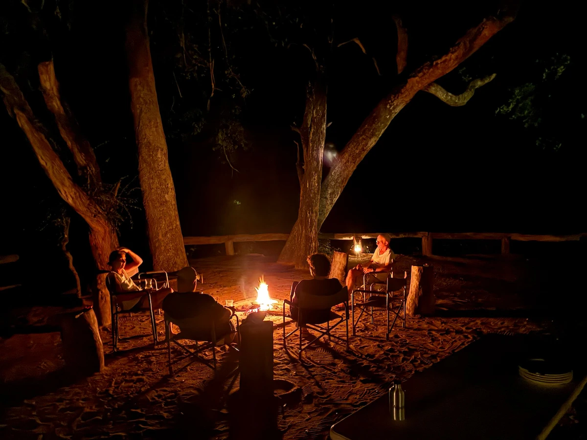 People relaxing by a campfire under the stars in the wild Big 5 Zinave National Park Mozambique Africa