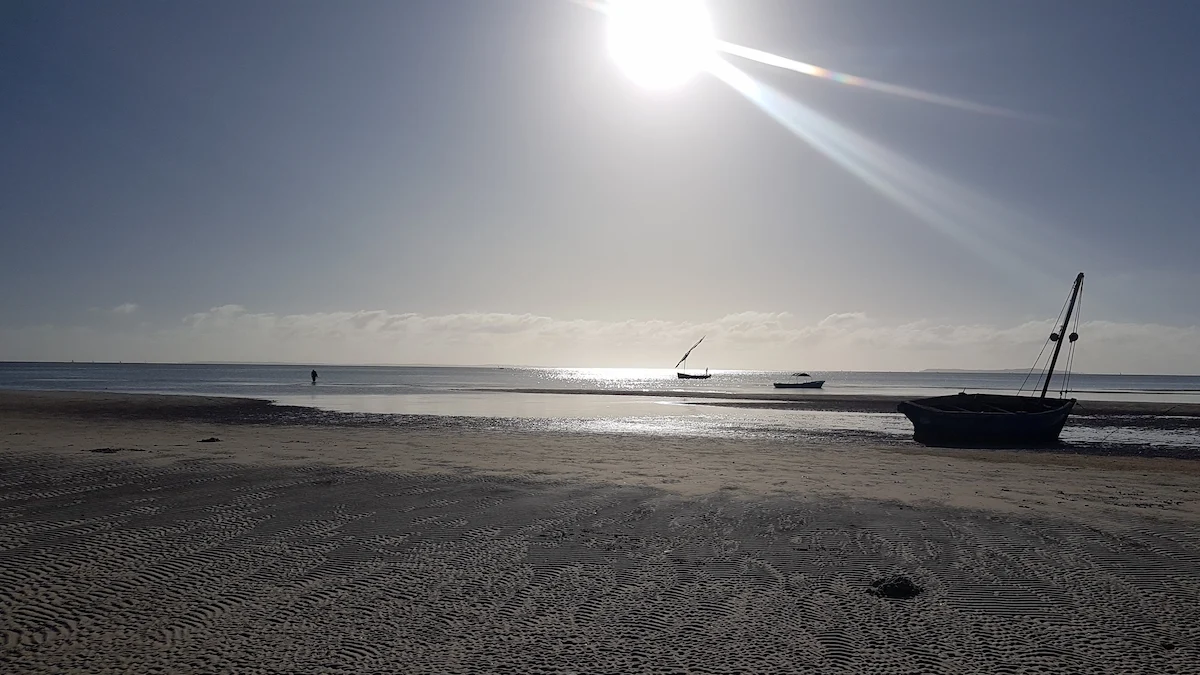 Dhow boat resting on the beach at sunrise in Vilanculos, Mozambique, with sunlight glistening on the ocean