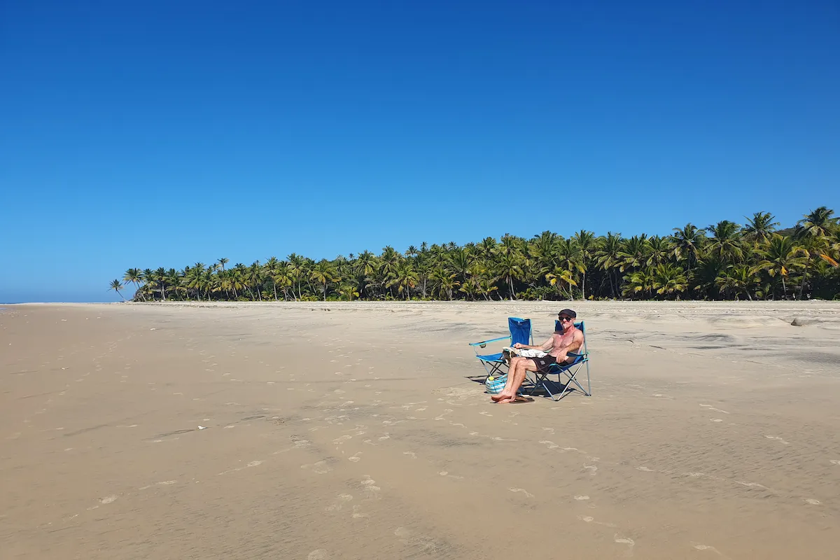 Dhow cruise Mozambique Man sitting on an unspoiled white beach full of coconut palms in Morrungulo Mozambique
