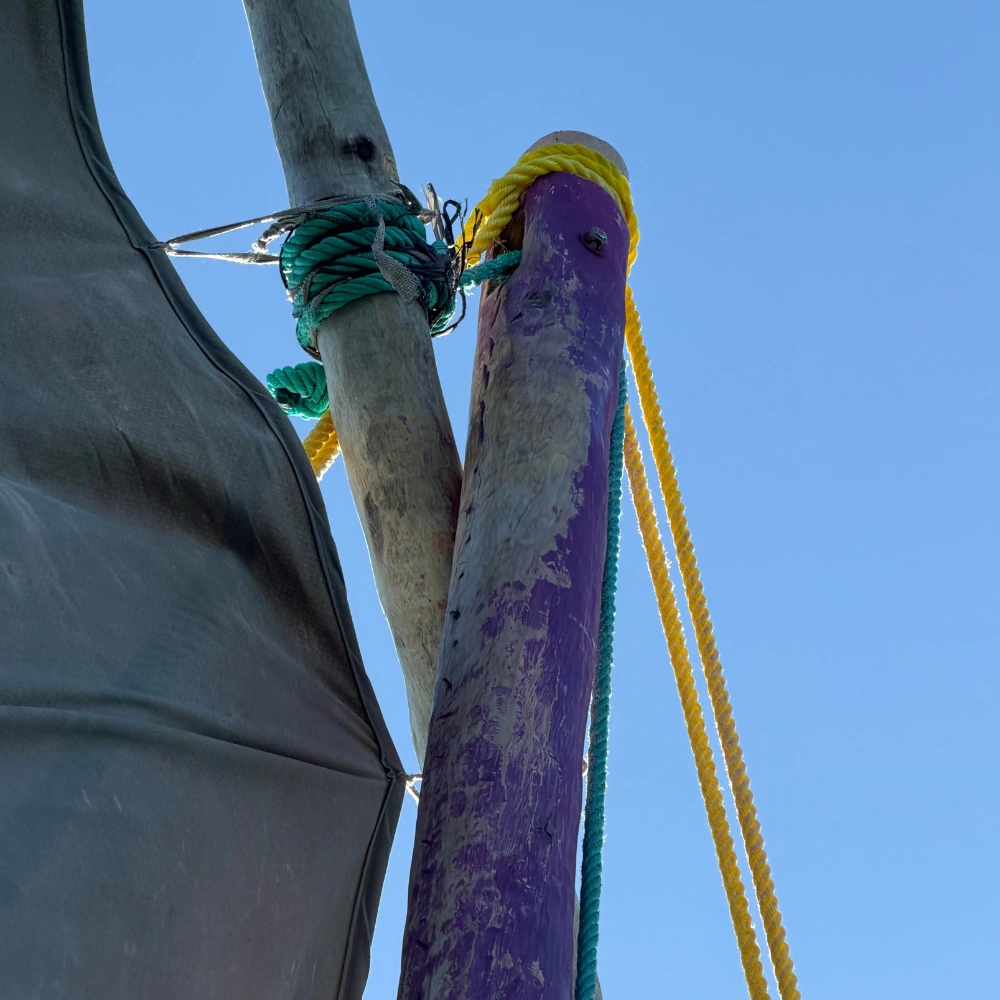 Kleurrijke masten van een dhow-boot in Mozambique Kleurrijke houten palen en touwen van een traditionele dhow-boot tegen een blauwe lucht in Mozambique.